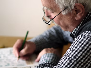 An elderly man doing a crossword puzzle